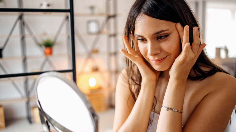 Woman smiling and looking into mirror after anti-wrinkle treatment