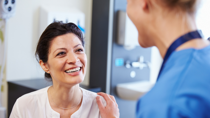 Woman smiling at dentist after missing teeth treatment